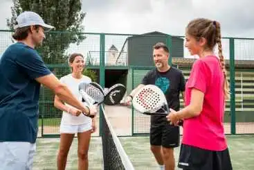 A mixed-age group of padel players enjoying a social match together on court