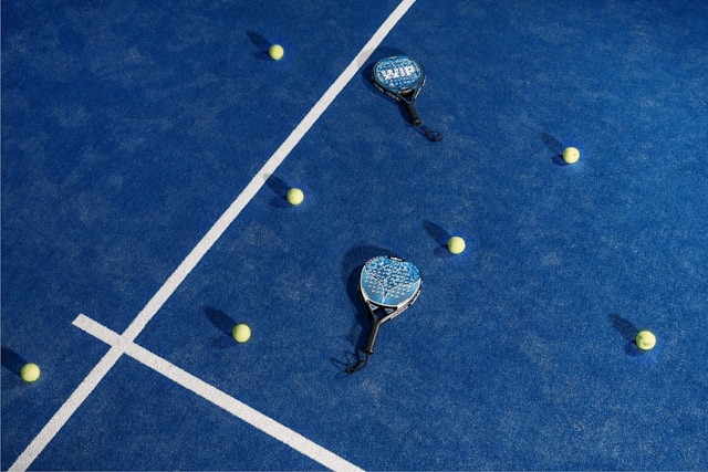 Modern padel court showing paddles, balls, and playing surface